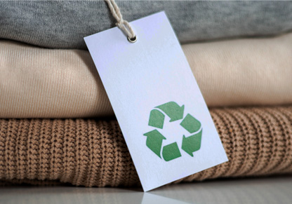 Three folded jumpers with a recyclable tag on them